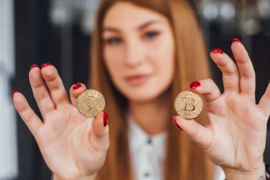 İki bitcoins elinde tutan ve kameraya, seçici odak seyir işkadını kırmızı ile çivi