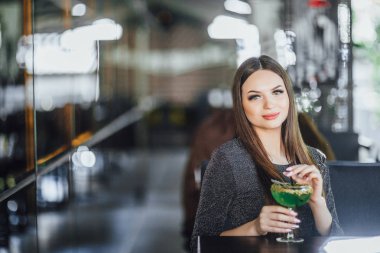 Modern kafede yaz terasında yeşil kokteyl içen genç kadının portresi, seçici odaklama