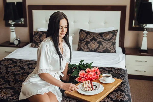 Красива Брюнетка Сидить Ліжку Кімнаті Скибочками Торта Троянд — стокове фото