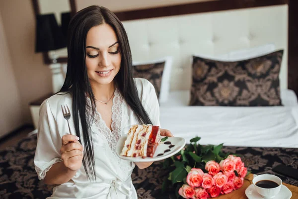 Wanita Berambut Cokelat Duduk Tempat Tidur Dan Makan Sepotong Kue — Stok Foto