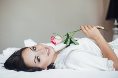 silah gül ile sabah yatakta yatan genç güzel esmer kadın