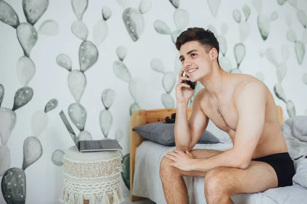 Junger Schöner Mann Sitzt Auf Bett Zimmer Und Telefoniert — Stockfoto