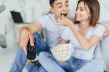 Genç çift evde Tv izliyor ve patlamış mısır yemek rahat kıyafetler içinde güzel