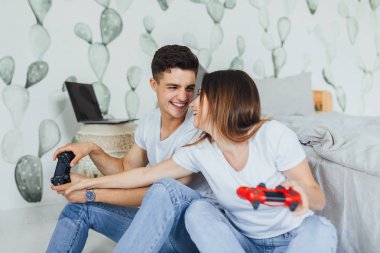 Yerde oturan ve joystick ile bilgisayar oyunu oynamak genç şirin çift