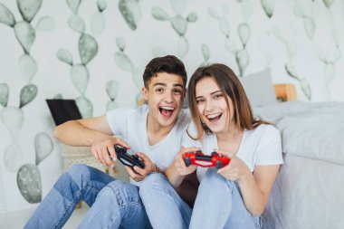 Yerde oturan ve joystick ile bilgisayar oyunu oynamak genç şirin çift