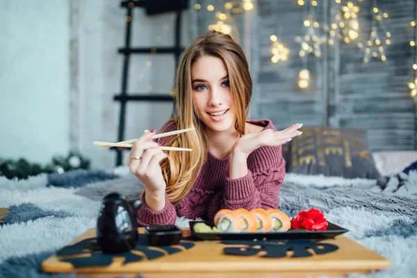 Yemek çubukları tutarak ve kameraya gülümseyen sarışın kadın