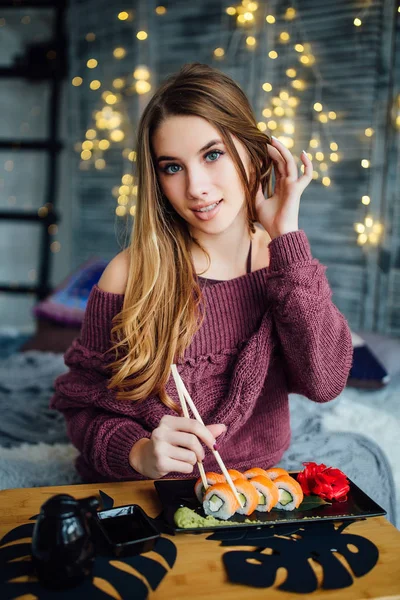 年轻的美丽的女人吃寿司卷用筷子 — 图库照片