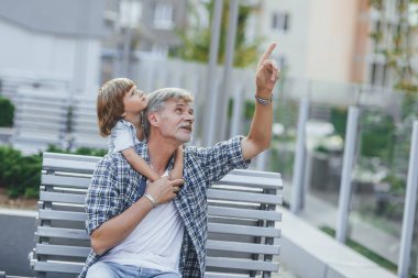 Büyükbaba çocuk bina yakındaki bankta için ilginç bir şey gösteren