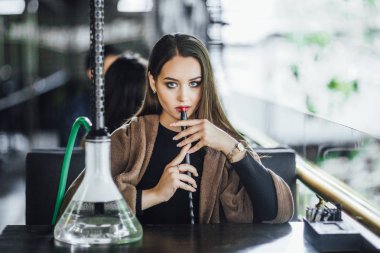 Modern restoranın yaz terasında battaniye ve sigara nargile ile kaplı genç kadın