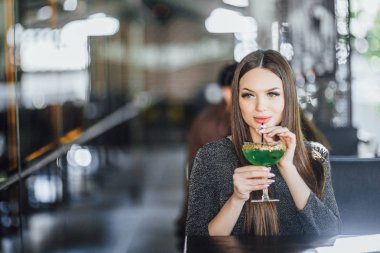 Modern kafede yaz terasında yeşil kokteyl içen genç kadının portresi, seçici odaklama