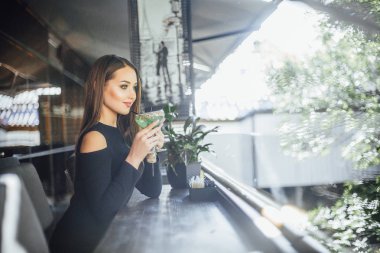 Yaz terasında ferahlatıcı kokteyl içme genç çekici kadın 