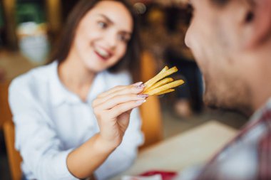 Gülümseyen, adam patates lokanta kafede besleme genç güzel esmer kadın