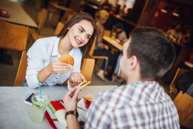Fast food restoranında yemek ve eğlence, seçici odak sahip genç güzel Çift