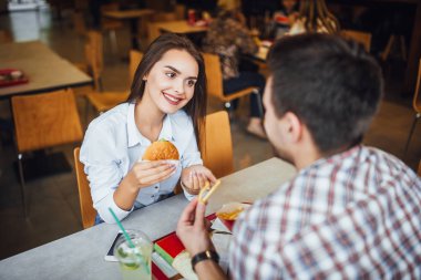 Fast food restoranında yemek ve eğlence, seçici odak sahip genç güzel Çift