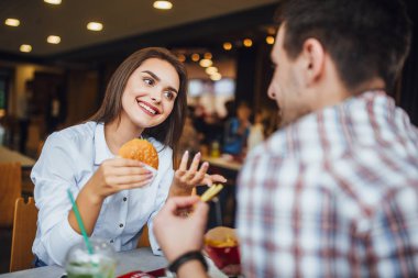 Fast food restoranında yemek ve eğlence, seçici odak sahip genç güzel Çift
