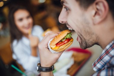 Peynir kadın, seçici odak arka plan üzerinde beyaz delikanlı lezzetli yeme hamburger