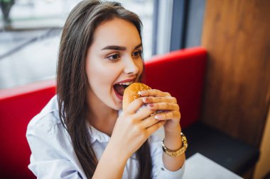 mutlu yüz burger yemek fast food café'genç esmer kadın