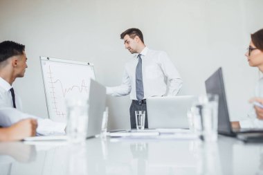 Modern konferans odasında iş arkadaşları için sunum yapan genç adam, seçici odaklanma
