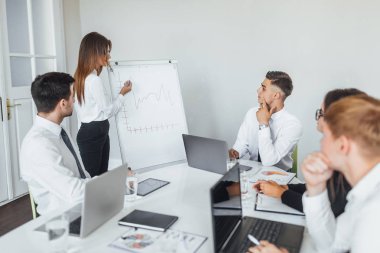 Genç modern iş kadını modern konferans salonundaki meslektaşlarına planı sunuyor.