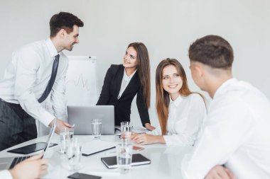 Genç ve başarılı iş ekibi modern konferans odasında gülümseyip iş konularını tartışıyor ve seçici bir şekilde odaklanıyor.