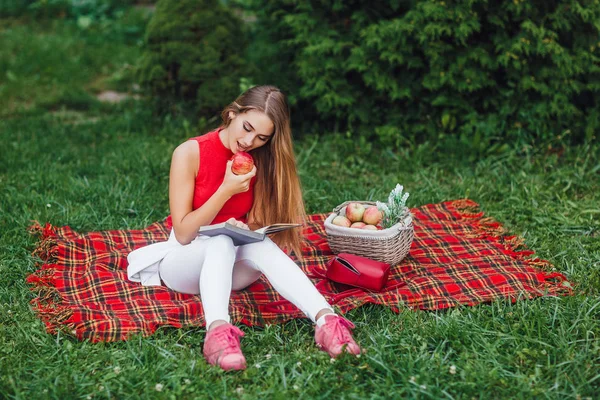 Ξανθιά Γυναίκα Που Διαβάζει Βιβλίο Και Διατροφικές Apple Στο Πάρκο — Φωτογραφία Αρχείου