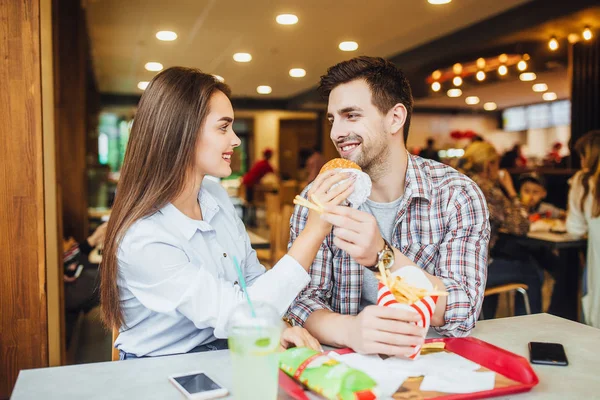 Seven genç çift birbirlerine hamburger ve patates, fast food Restoran pencerede yakınındaki gülümseyen besleme