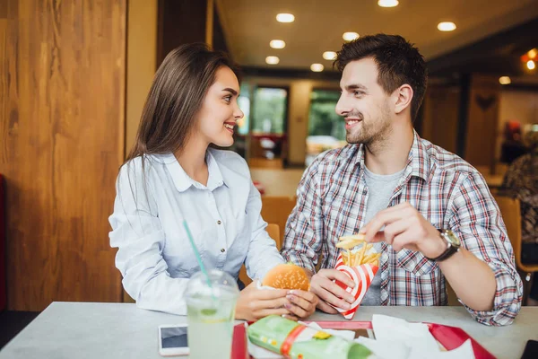 Hermosa Pareja Sonriente Consiguiendo Placer Mientras Come Hamburguesa Patata Restaurante —  Fotos de Stock