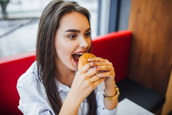 Ung Brunett Kvinna Äta Burgare Med Glada Ansikte Snabbmat Café — Stockfoto