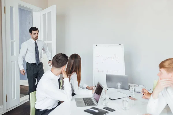 Unexpected appearance of director at business meeting in modern conference room