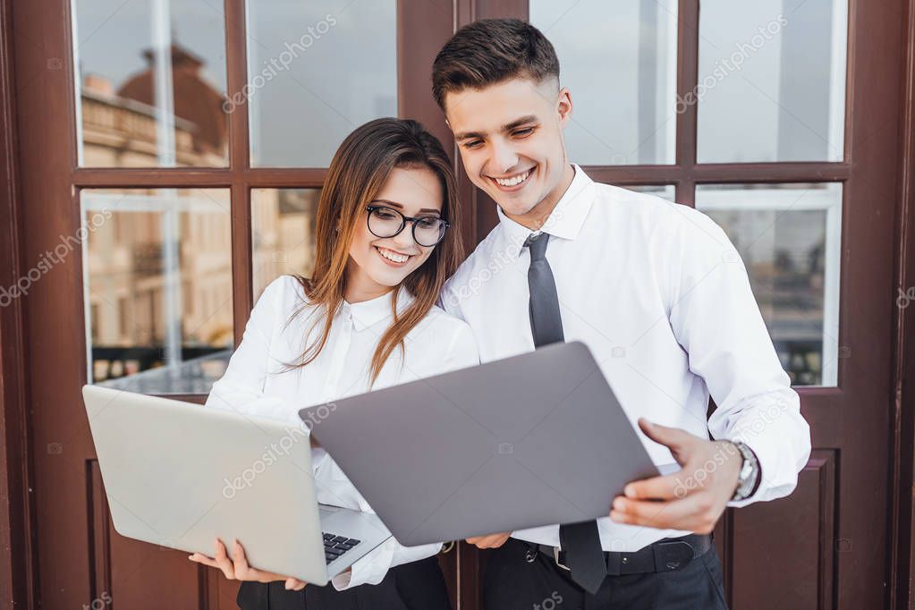 Young beautiful woman with glasses and man with laptops in hands smiling