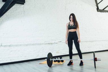 Modern beyaz spor salonunda halter kalacak atletik esmer kadın