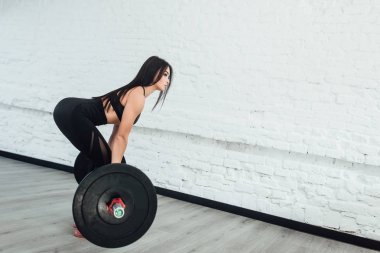 genç kadının geri dönüş spor salonunda ağırlık kaldırma egzersiz yapması