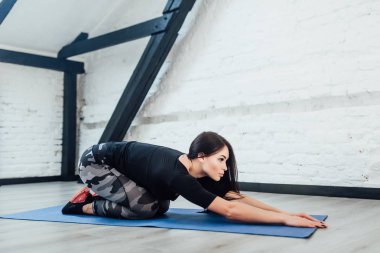 Esmer ve sportif kadın mavi mindere germe