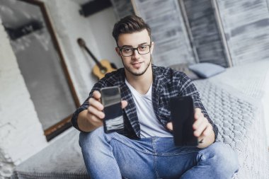 Çatı odasında iki cep telefonu karşılaştırma gözlüklü genç yakışıklı blogger