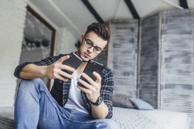 Çatı odasında iki cep telefonu karşılaştırma gözlüklü genç yakışıklı blogger