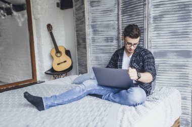yatakta dizüstü blog için yeni yazı yazma gözlüklü genç yakışıklı blogger 