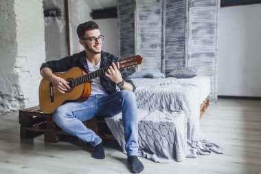 gülümseyen ve gitar yatakta Studio ile poz gözlük yakışıklı adam 