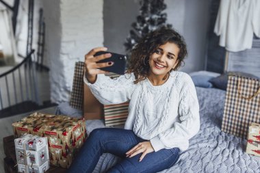 Video blog cep telefonu alarak ve yeni yıl hediye loft tarzı oda içinde gösterilen genç güzel blogger