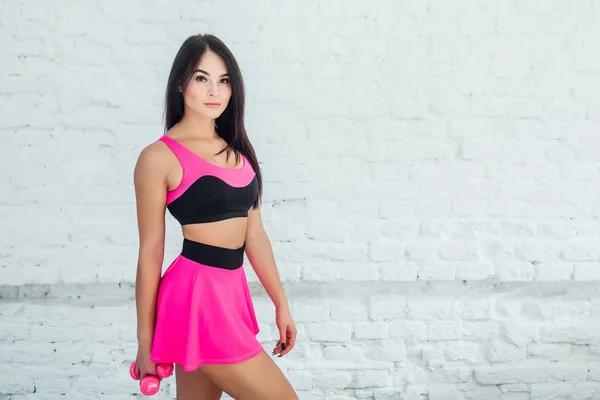 Young woman in pink sportswear on white background