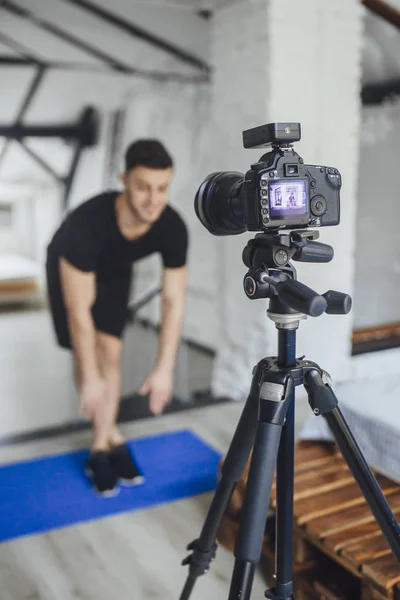 handsome fitness blogger recording video for blog and showing exercises for workout