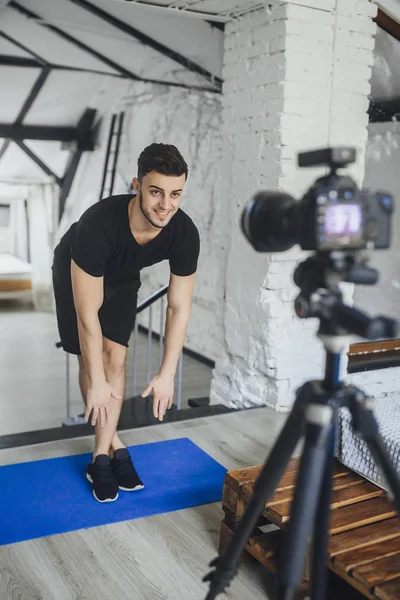 young fitness blogger shooting video for blog and telling basic rules during workout in loft style room