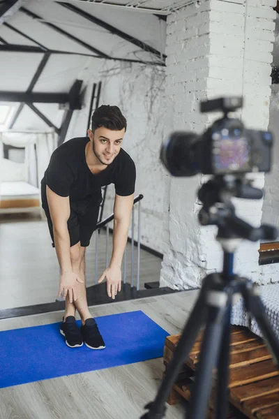 handsome fitness blogger recording video for blog and showing exercises for workout