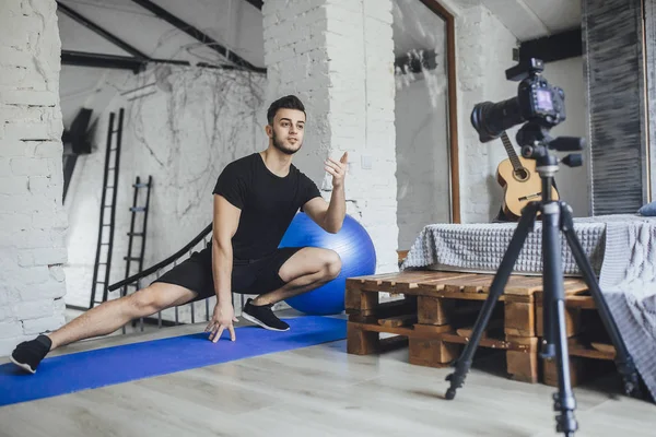 young fitness blogger shooting video for blog and telling basic rules during workout in loft style room