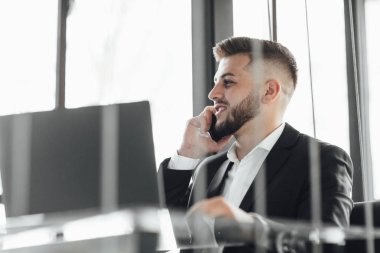 modern ofiste akıllı telefonda konuşan işadamı