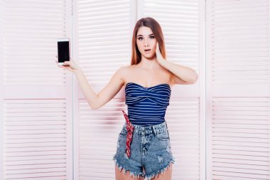pembe arka planda akıllı telefon ile mavi mayo kadın 