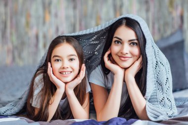 Yatakta yatan başları üzerinde ekose olan iki kız kardeş