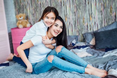 Evde yatakta oynayan iki mutlu kız, seçici odak