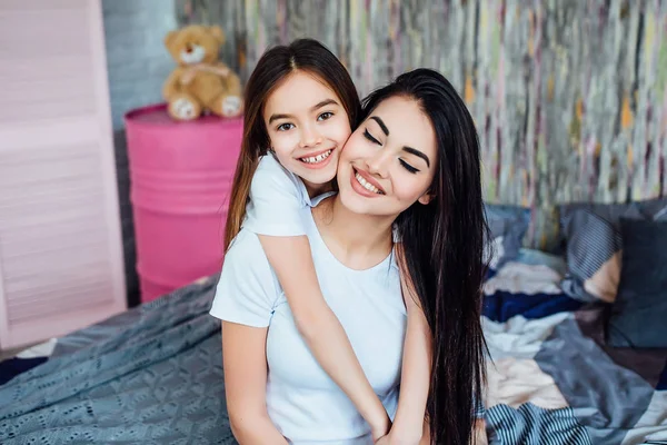 Evde yatakta oynayan iki mutlu kız, seçici odak