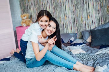 Evde yatakta oynayan iki mutlu kız, seçici odak