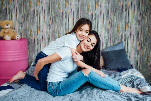 Evde yatakta oynayan iki mutlu kız, seçici odak